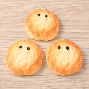 Close-up of three miniature resin bread charms with cute faces on light wood background
