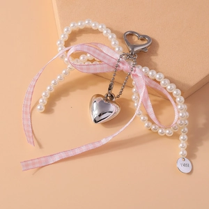 Détail d'un porte-clés en perles avec nœud en ruban rose à carreaux et pendentif cœur