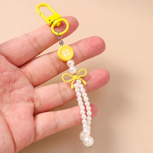 Porte-clés tendance avec bouton jaune, perles nacrées et nœud décoratif jaune