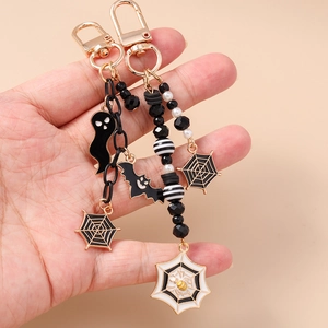 Halloween beaded ghost keychain set with black bats, spider webs and tassels on light background