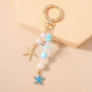 Detail van gouden zeester hanger met blauwe kralen en een ronde veersluiting sleutelhanger
