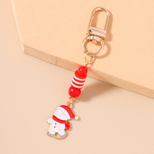 Detailed view of Christmas snowman keychain with red and white beads on a soft pink stand