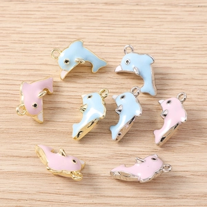 Macro-opname van blauwe en roze emaille dolfijn hangers met goud en zilver metalen ringen