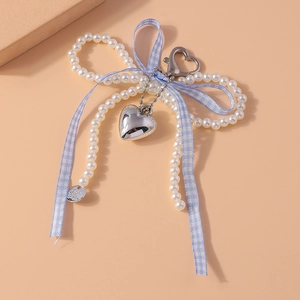 Détail du porte-clés nœud en perles blanches avec ruban bleu et breloques cœur argentées