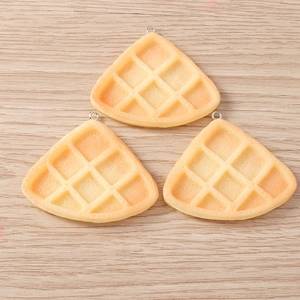 Detail view of waffle food charms with grid textures and silver metal hooks for DIY