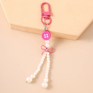 Détail du porte-clés à nœud rose avec glands de perles et boucle en métal poli