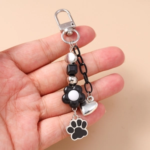 Dettaglio portachiavi creativo con zampa di gatto nera, fiori e ciondolo a cuore