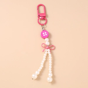 Vue détaillée du porte-clés à bouton rose avec franges de perles et nœud en ruban