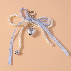 Détail du porte-clés à nœud en perles avec ruban à carreaux bleu et pendentif cœur