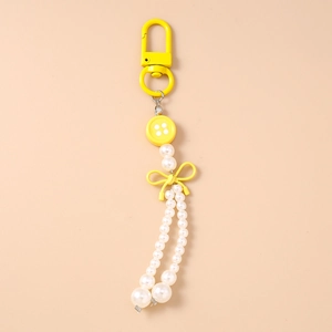 Détail d'un porte-clés jaune avec nœud et pampille de perles blanches élégant