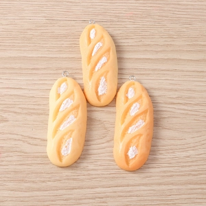 Detail view of miniature resin baguette charms with silver metal rings on a wood surface