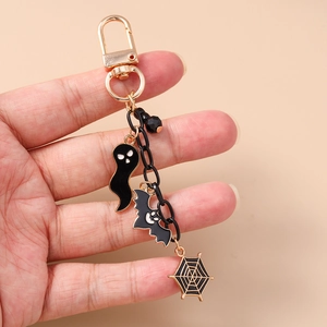 Detail of Halloween keychain with black ghost, bat and spider web enamel charms on a gold clip
