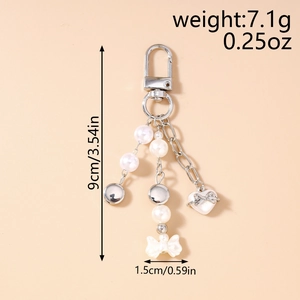 Détail porte-clés avec pendentifs cœur et nœud, dimensions 9cm x 1,5cm et poids de 7,1g