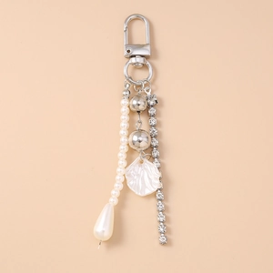 Detail view of rhinestone chain, pearl tassel and shell pendant on silver lobster clasp