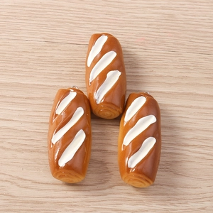 Close-up of three miniature resin baguette pendants with realistic caramel texture