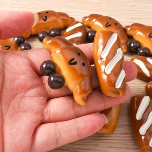 Miniatuur hars brood bedeltjes met gezichtjes in de hand gehouden voor schaalweergave