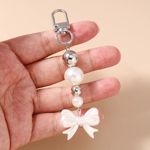 Vue détaillée d'un porte-clés perlé avec des perles blanches et un pendentif nœud