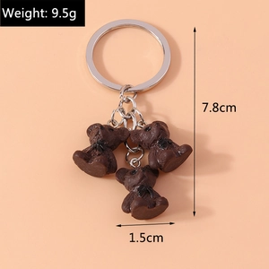 Détail du porte-clés ours 3D avec anneau métallique et nœuds papillon noirs élégants