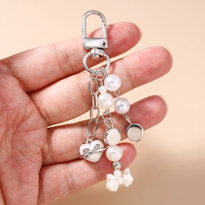 Gros plan du porte-clés perle élégant avec charms cœur et nœud en métal argenté