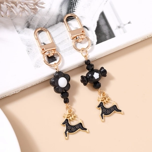 Detailed macro view of black floral and elk charms with golden metal hooks on bag pendant