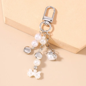 Détail d'un porte-clés à pampilles avec perles blanches, cœur en métal et nœud élégant