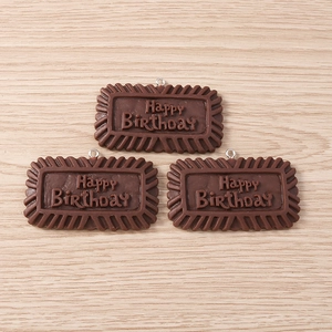 Macro detail of chocolate-themed resin pendants with Happy Birthday embossed design