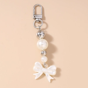 Détail du fermoir argenté avec perles blanches et pendentif en forme de nœud blanc