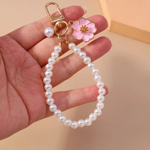 Detail of pink enamel cherry blossom and white pearls on a gold lobster clasp keychain