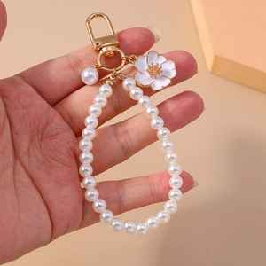 Detail of elegant pearl keychain with white enamel flower charm and gold metal hook