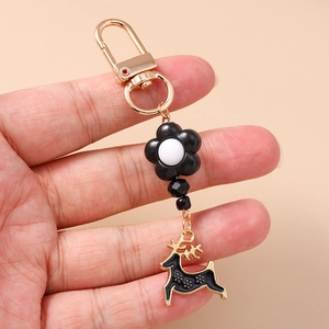 Detailed view of black enamel reindeer charm with flower motifs and golden metal clasp