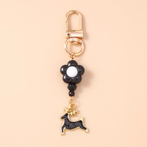 Close-up of golden lobster clasp with black floral beads and reindeer pendant charm