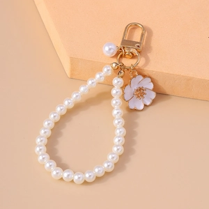 Macro detail of white enamel flower pendant and elegant pearl ring keychain accessory
