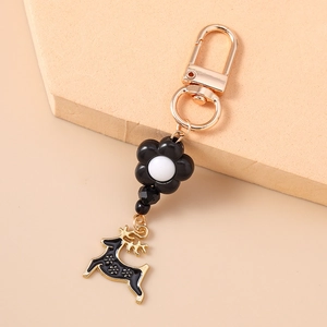 Close-up of a gold metal keychain featuring a black flower bead and a reindeer pendant