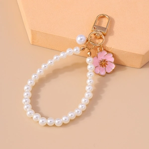Detail view of pearl keychain featuring a delicate pink enamel cherry blossom floral pendant