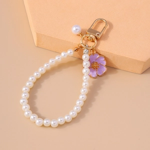 Detail of elegant pearl keychain featuring a purple enamel flower charm and golden clasp