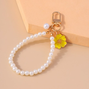 Detail of yellow flower pendant with white pearls and golden clasp for bags