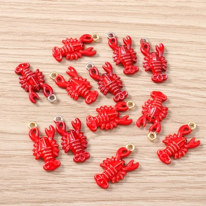 Detailed close-up of red enamel lobster pendants with metal rings on a wooden surface