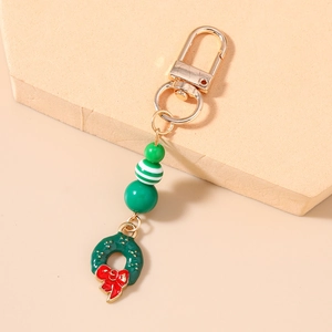 Christmas beaded keychain with green wreath charm and golden clasp on stone pedestal