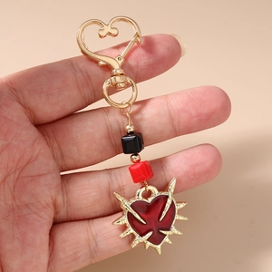 Gothic heart keychain detail featuring red enamel heart with golden thorn accents
