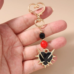 Detail showing Gothic punk heart keychain with golden spikes and red beads on hand
