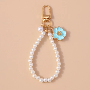 Detail of blue enamel flower pendant with white pearl chain and gold-tone metal key ring