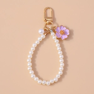 Detail of white pearl keyring with a purple enamel cherry blossom and golden clasp