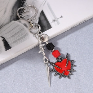 Detail of gothic sword heart keychain with silver metal spikes and red enamel heart pendant