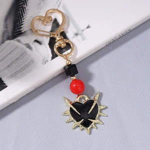 Detailed close-up of gothic sword and heart keychain with red beads and thorn heart pendant