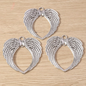 Détail de breloques ailes d'ange plaquées argent avec motif cœur évidé pour bijoux DIY
