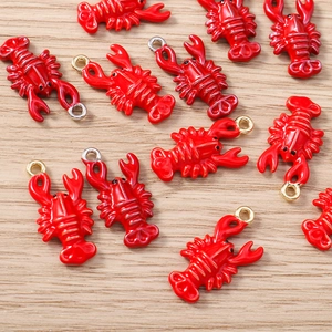 Macro detail of red lobster enamel charms with gold and silver loops for DIY jewelry