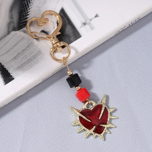 Macro detail of gothic sword heart keychain with golden spikes and red resin
