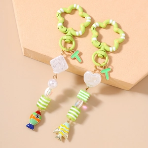 Détail de porte-clés poisson en émail coloré avec perles rayées et pendentif lettre T vert