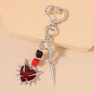 Detail of gothic thorn heart keychain with red enamel and silver sword spike charms