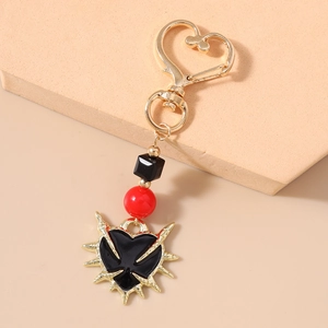 Macro shot of Gothic sword heart keychain with golden thorns and red beads detail